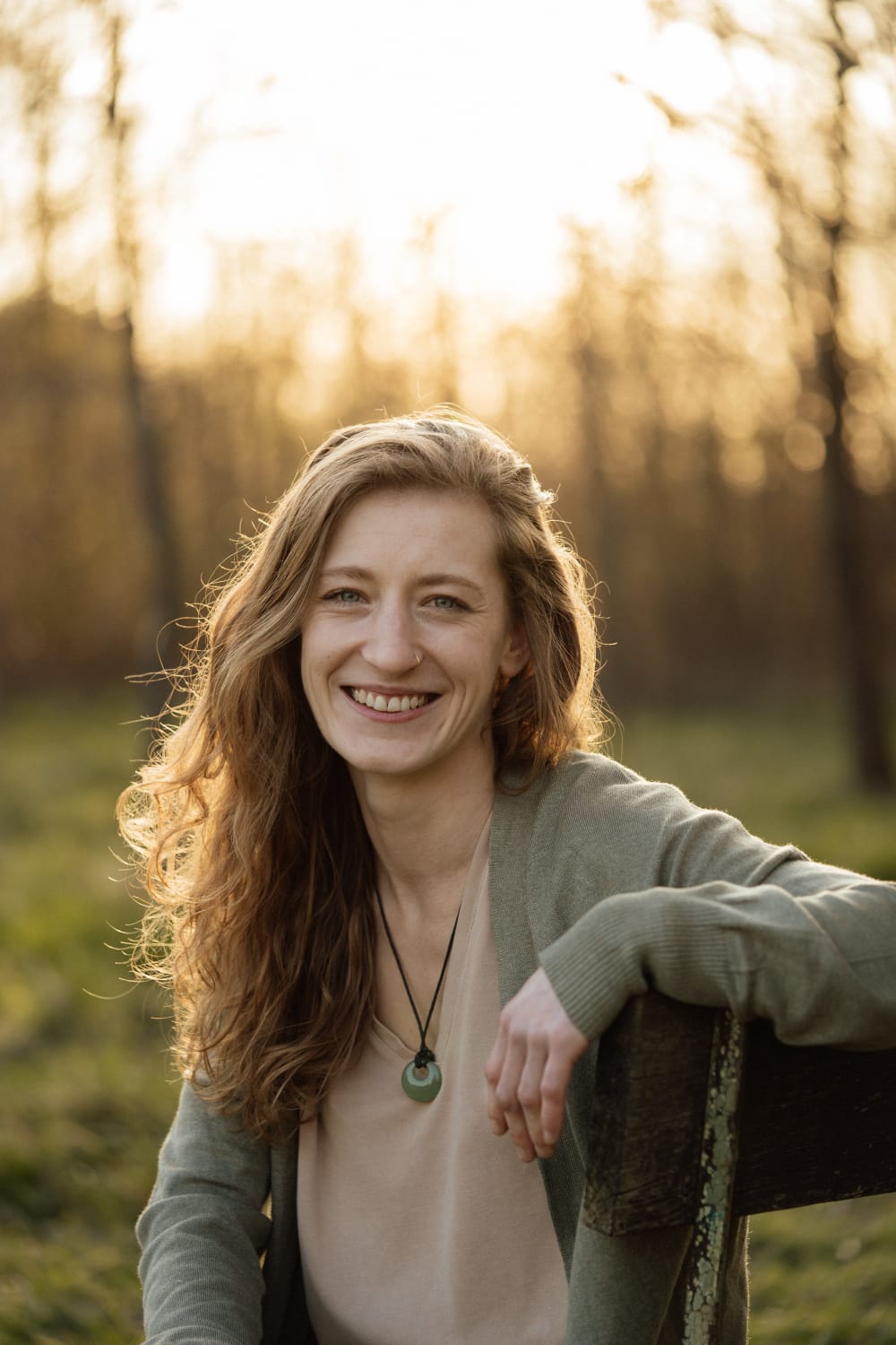 Kinesiologie Sonja Krusche auf einer Bank mit Sonne im Hintergrund